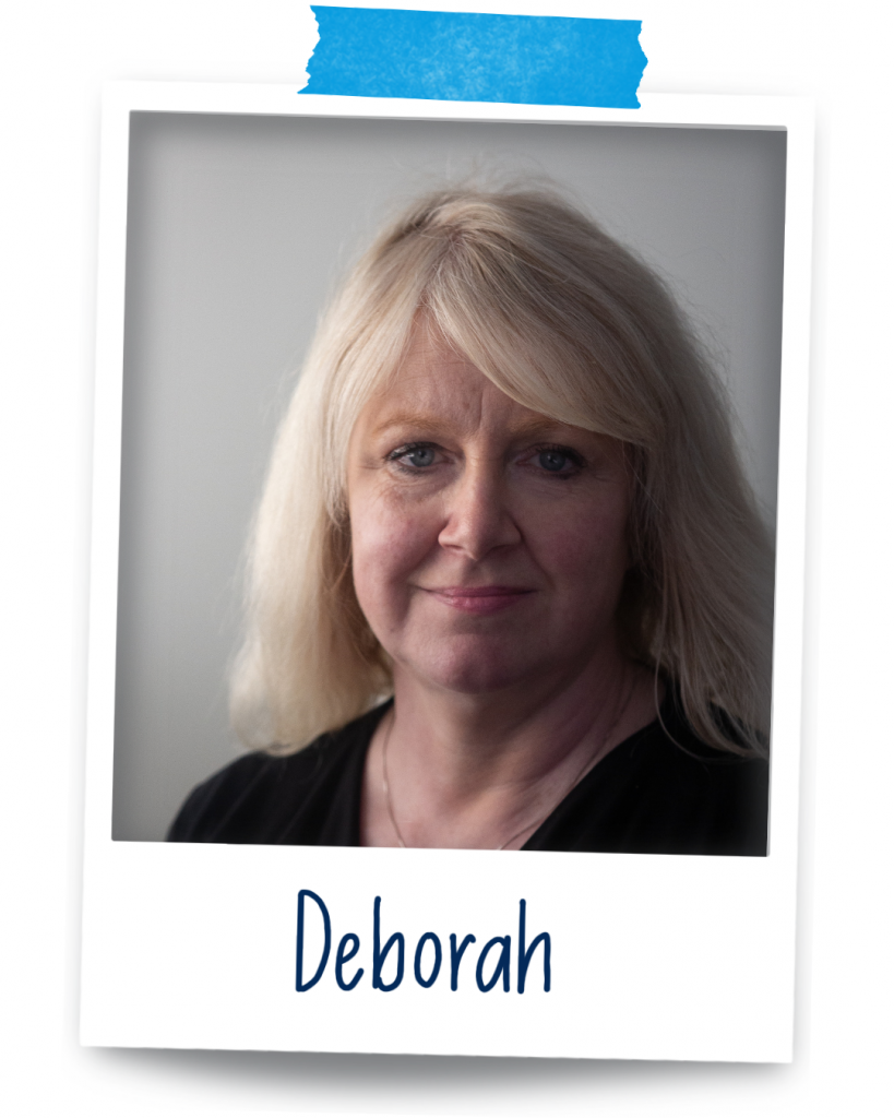 Deborah, a petite fair skinned woman in her 50's with blonde hair wearing a black top smiling at the camera.